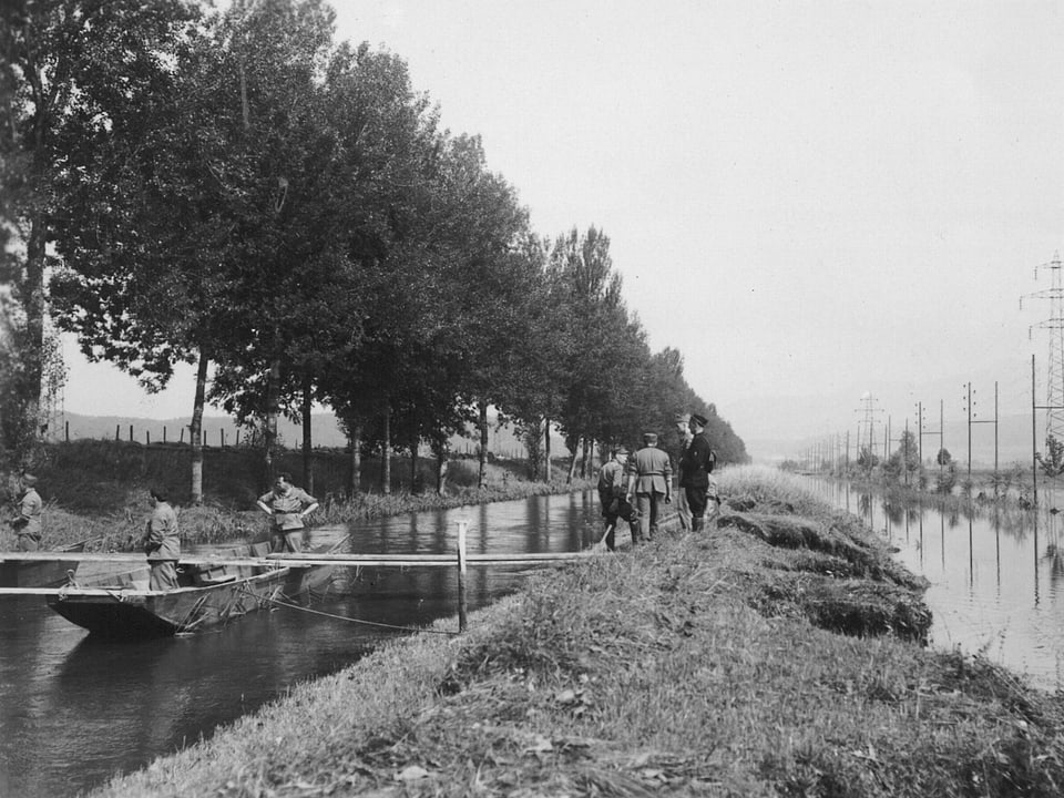 Schwarz-Weiss-Bild: Männer in einem Boot auf dem Fluss.
