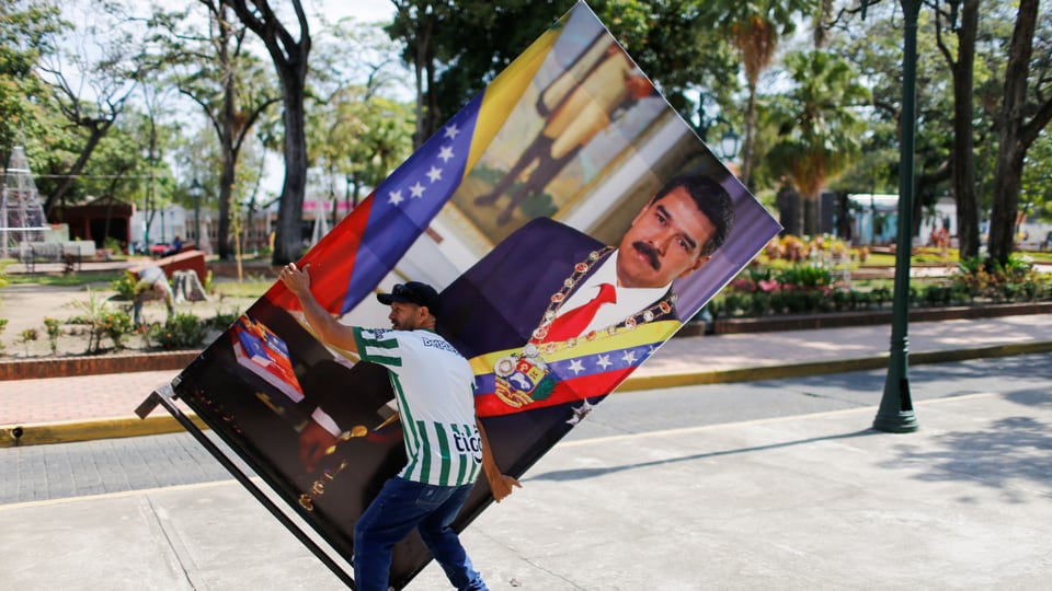 Ein Mann schiebt eine überlebensgrosse Abbildung Nicolas' Maduros vor sich hin