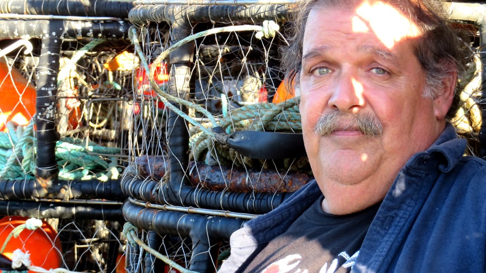 Fischer Larry Collins sitzt vor einem Gestell mit Fischer-Utensilien.