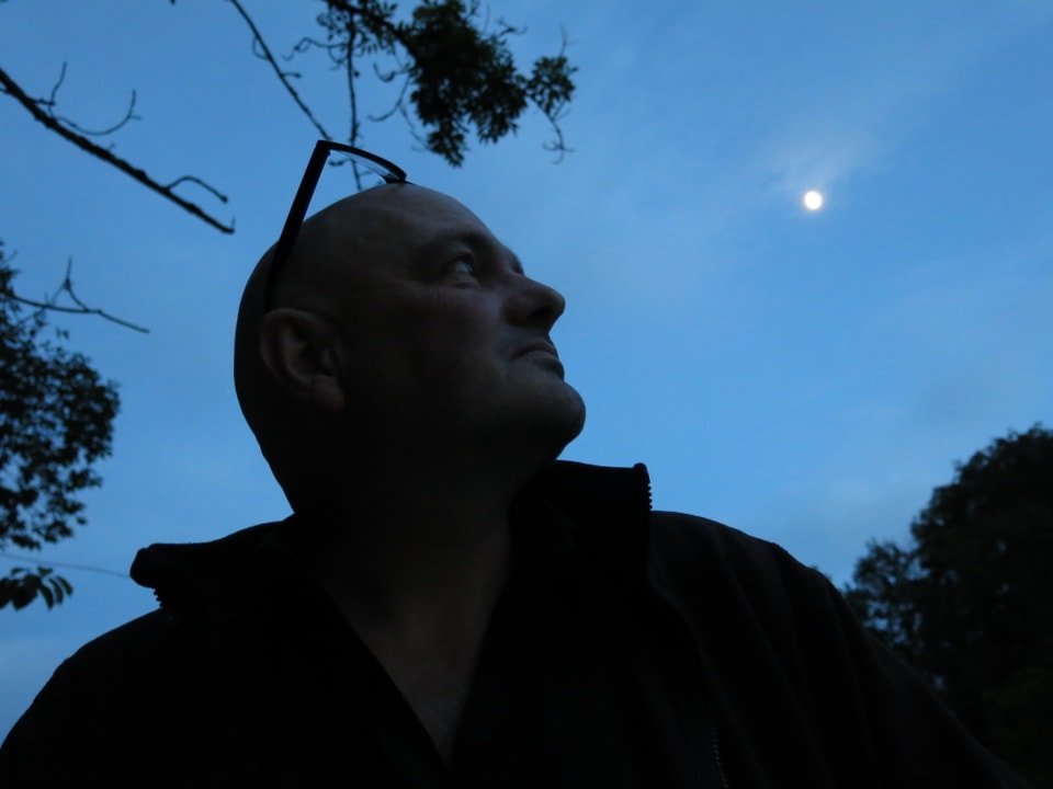 Der Musiker im Schatten. Über ihm am tiefblauen Himmel der Mond.  