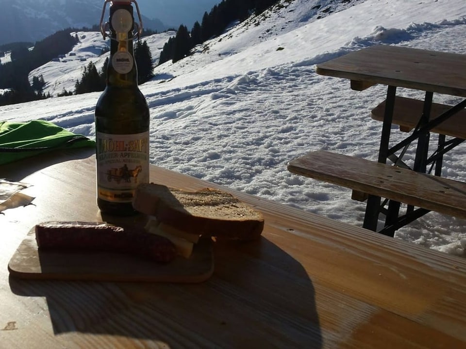 Most, Wurst und Brot auf Tisch bei Alp-Beizli im Winter.