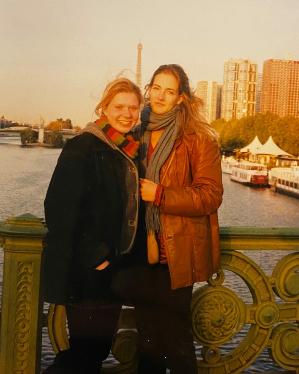 Zwei junge Frauen posieren auf einer Brücke in Paris.
