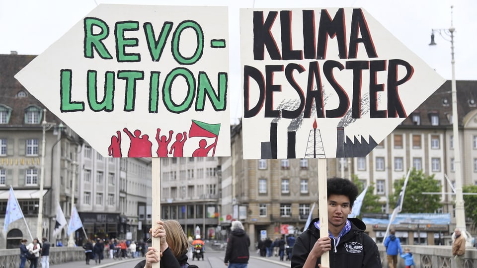Demonstranten halten Schilder mit der Aufschrift «Revolution» und «Desaster».