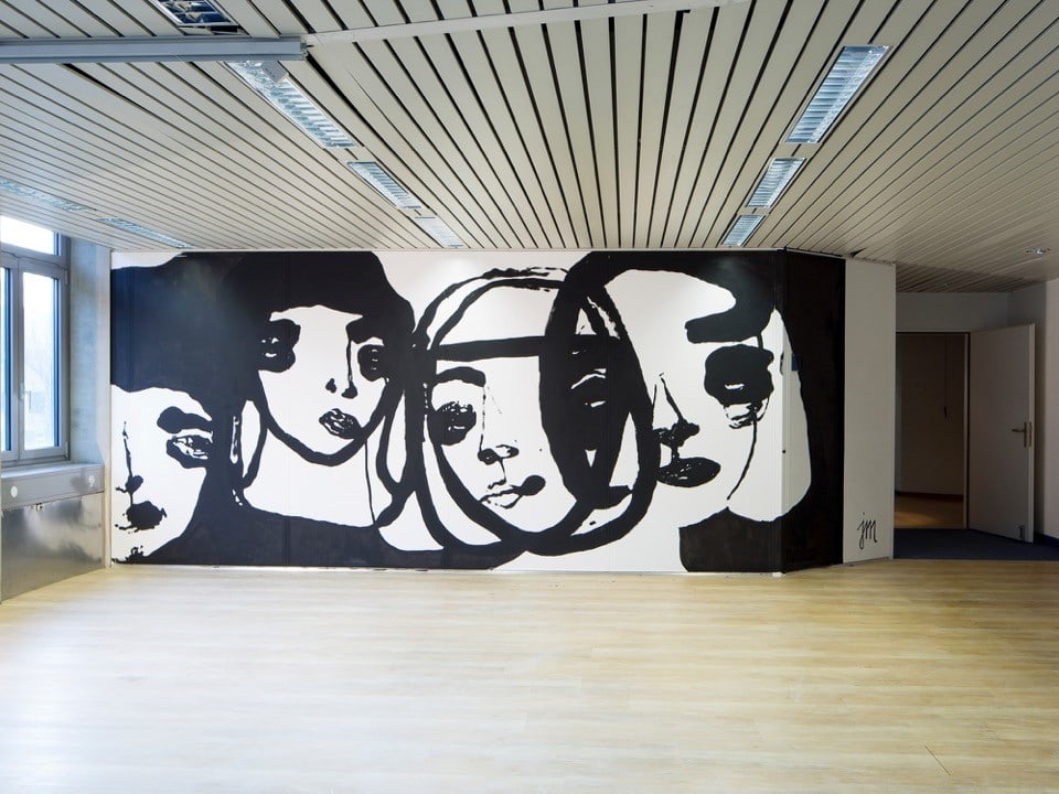 Künstler haben eine Wand in einem Baufälligen Gebäude mit Gesichern bemalt.