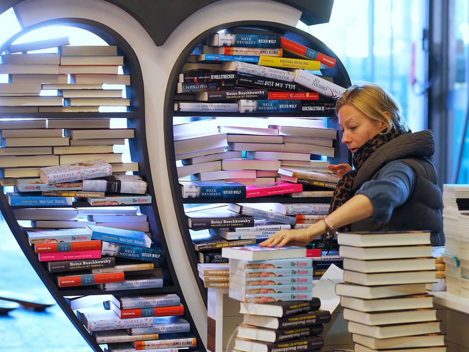 Eine Frau sortiert einen Bücherstapel.