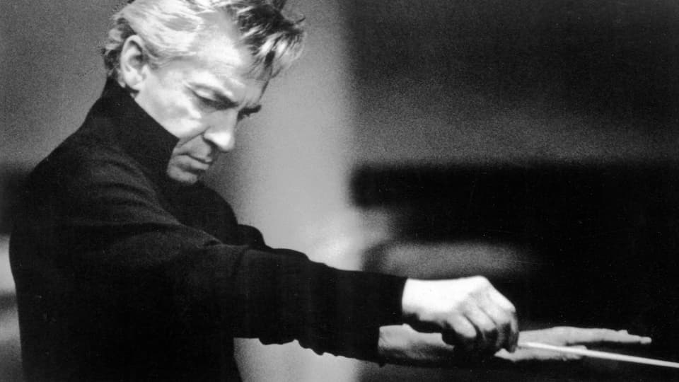 Schwarzweissfoto: Herbert von Karajan dirigiert.
