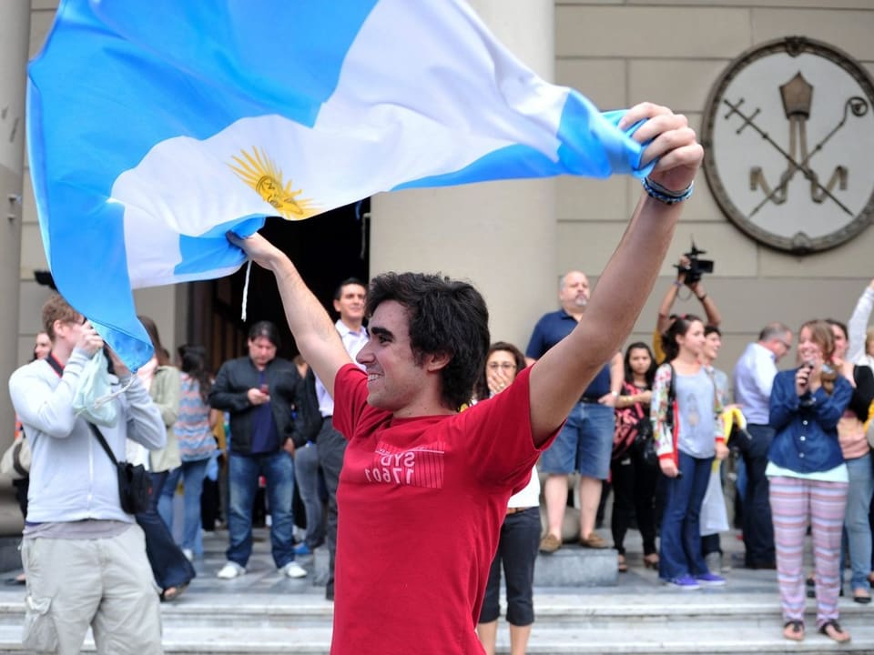 Mann mit argentinischer Flagge über dem Kopf.