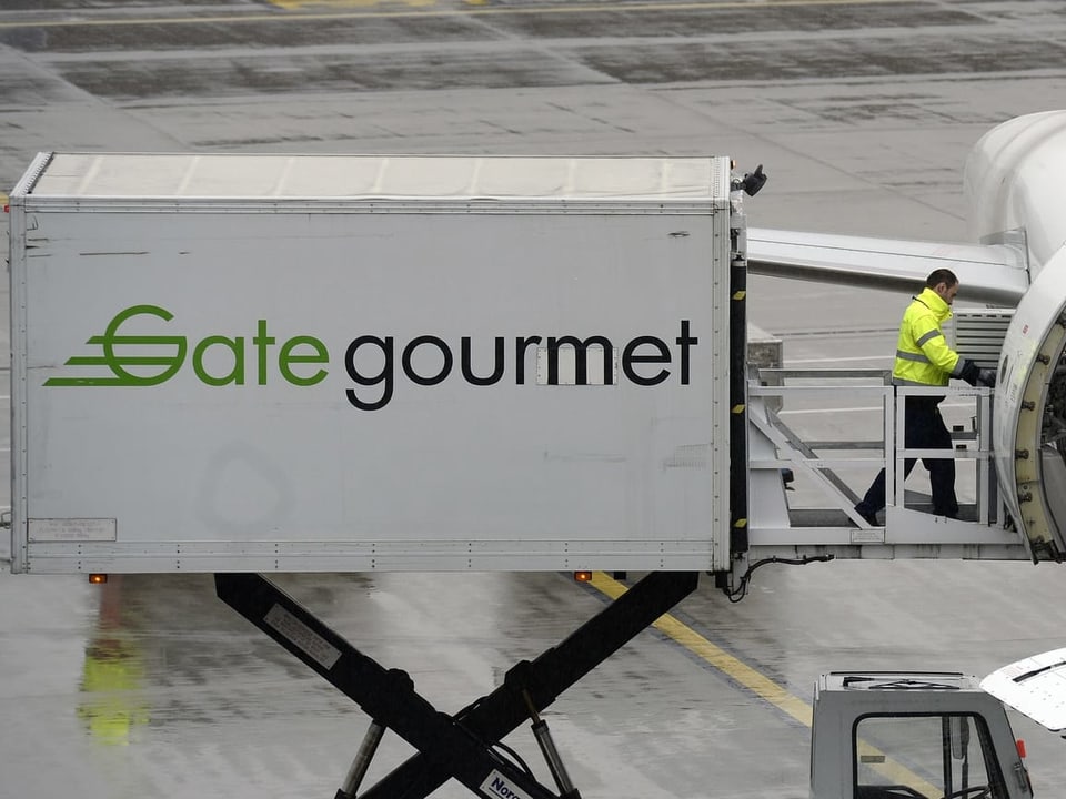 Gategourmet Container belädt ein Passagierflugzeug.