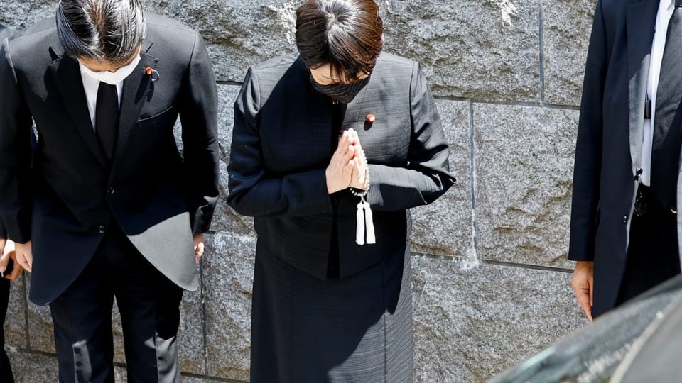 Vor dem Wohnhaus von Shinzo Abe verbeugen sich Menschen, als der Leichenwagen mit dem Körper von Abe vorbeifährt.