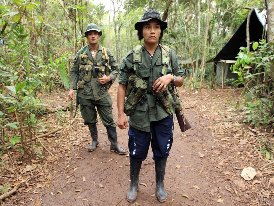 Eine weibliche Farc-Kämpferin bewacht zusammen mit ihrem Waffenfreund die Konferenz im Dschungel. 