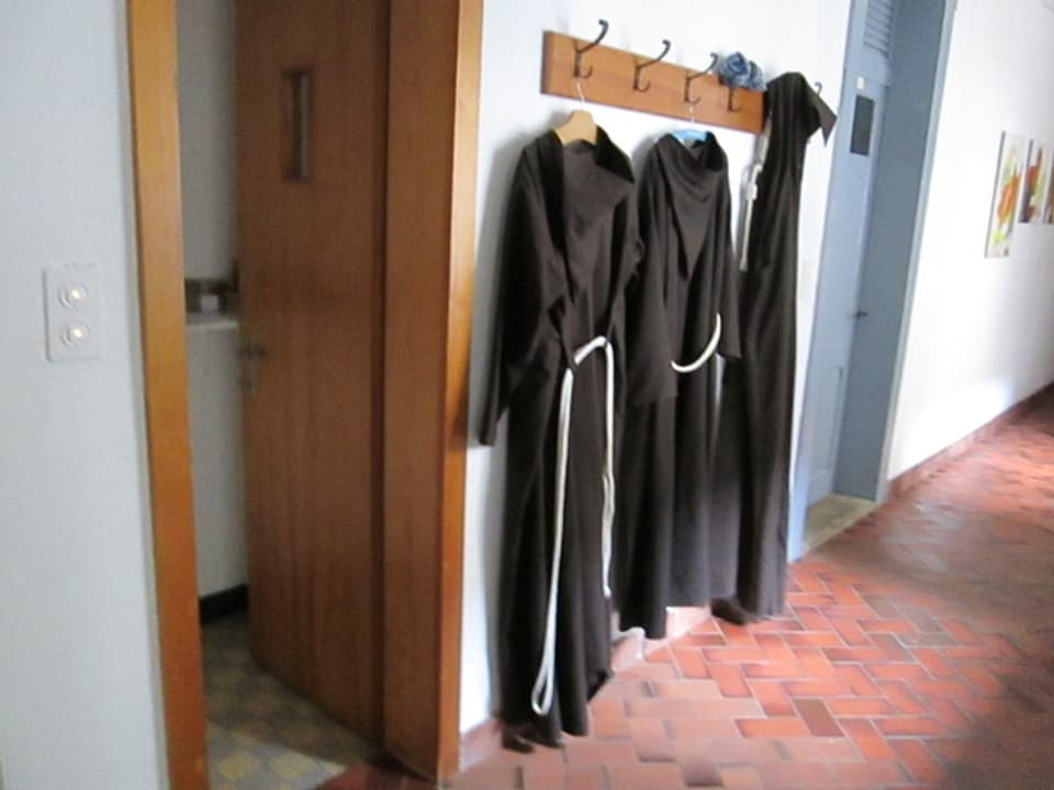 Klostergang mit drei Mönchskutten an der Garderobe.