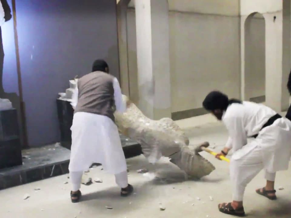 Zwei IS-Terroristen schlagen mit schweren Hämmern auf eine Statue ein.