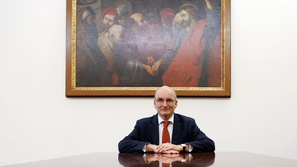 Der Chef der Vatikan-Bank, Ernst von Freyberg, sitzt an einem grossen Glastisch