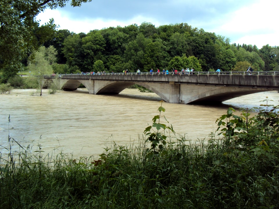 Brücke führt über einen braunen Fluss mit Hochwasser