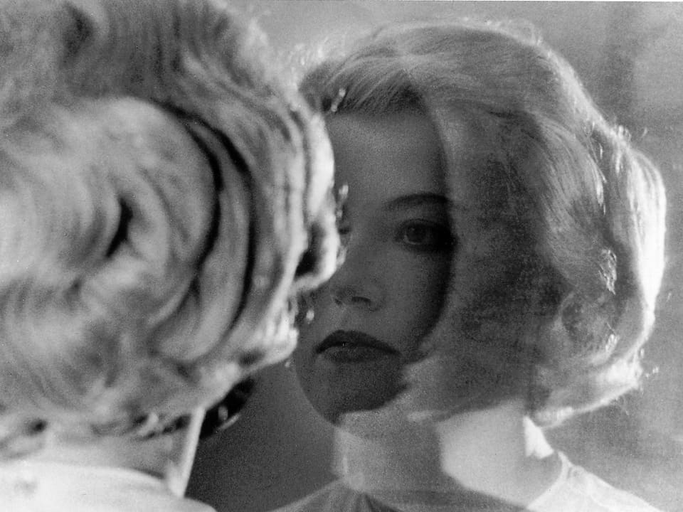 Eine Frau schaut sich im Spiegel an. Schwarz-weiss-Foto.