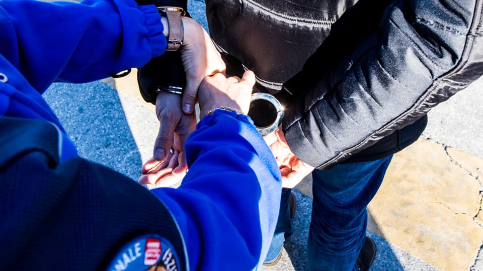 Polizist legt einer Person Handschellen an.
