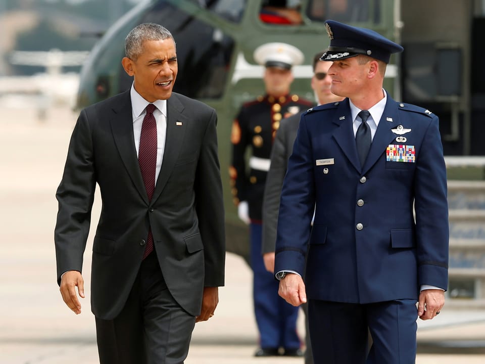 Präsident Obama und ein Miltär gehen von einem Helikopter weg