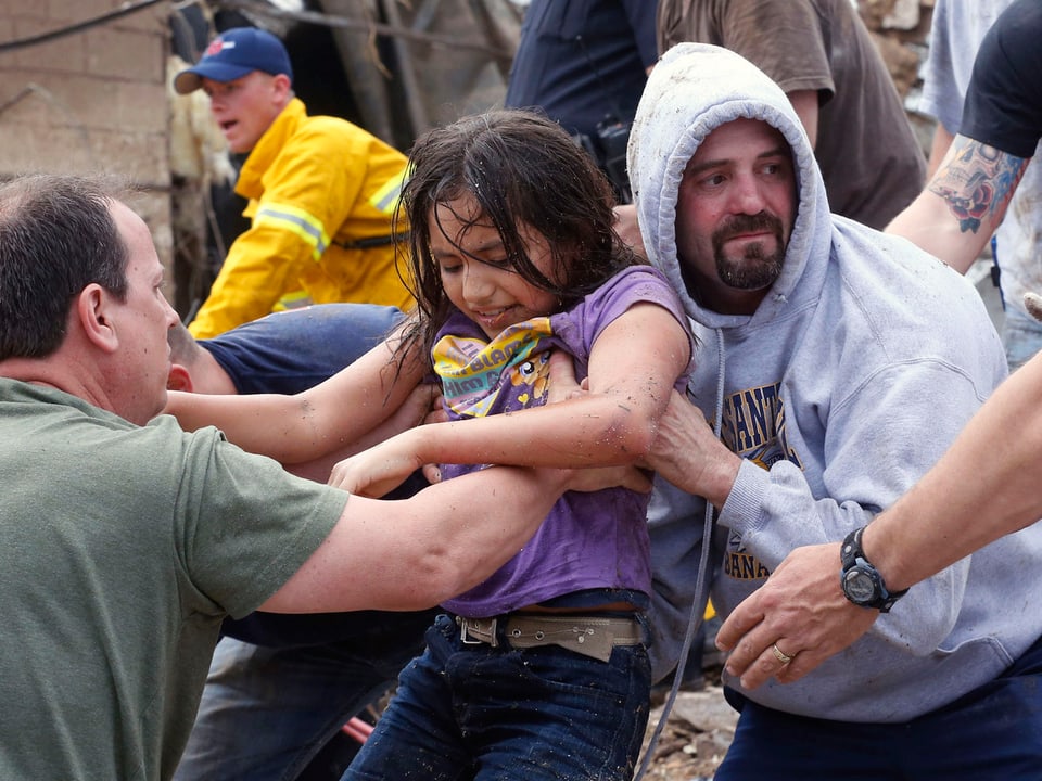 Helfer heben ein gerettetes Mädchen aus den Trümmern