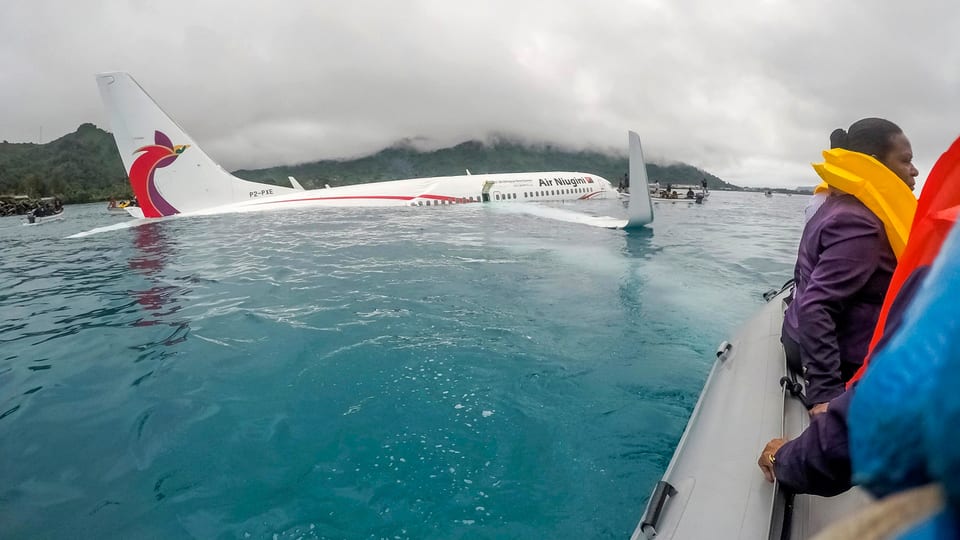 Flugzeug im Wasser, daneben Rettungsboote. 