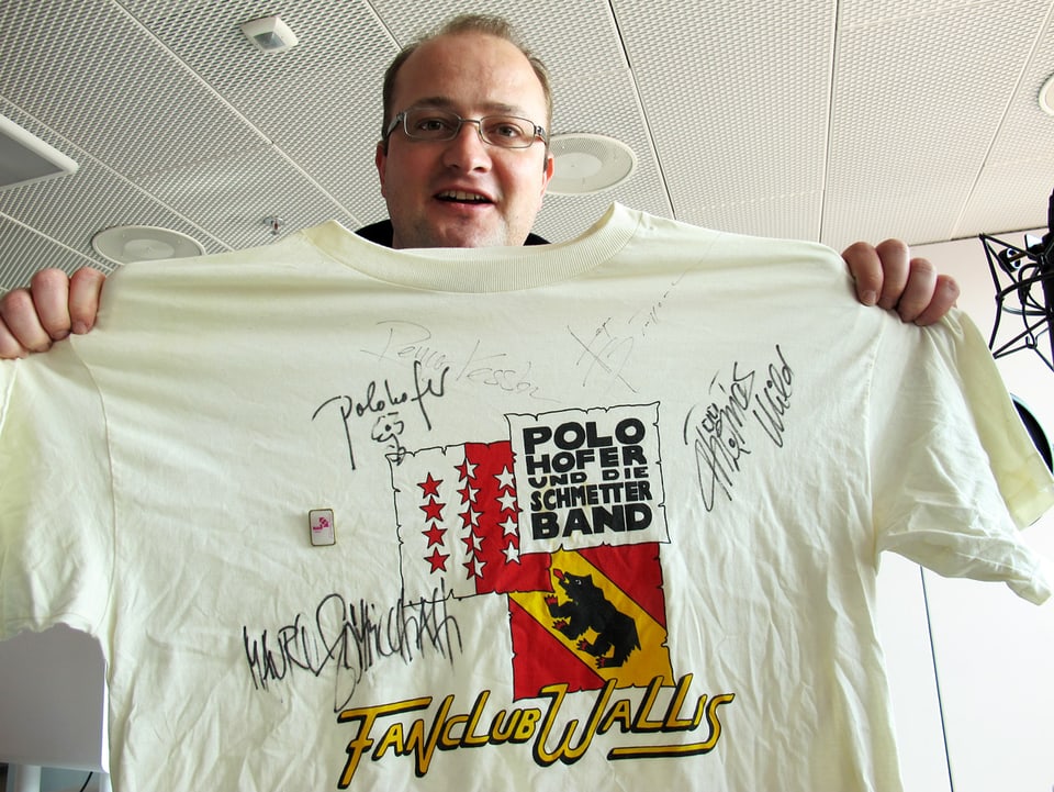 Michael Brunner streckt das signierte Fanclub-T-Shirt in Richtung Kamera.