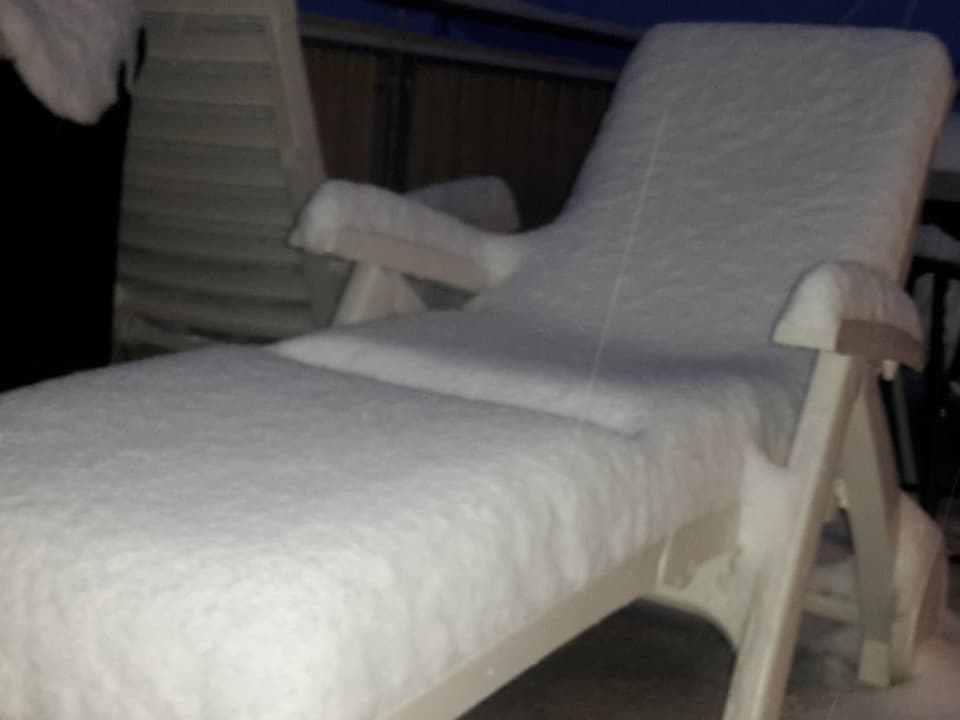 Auf einem Gartenliegestuhl liegt ein dickes Schneepolster.