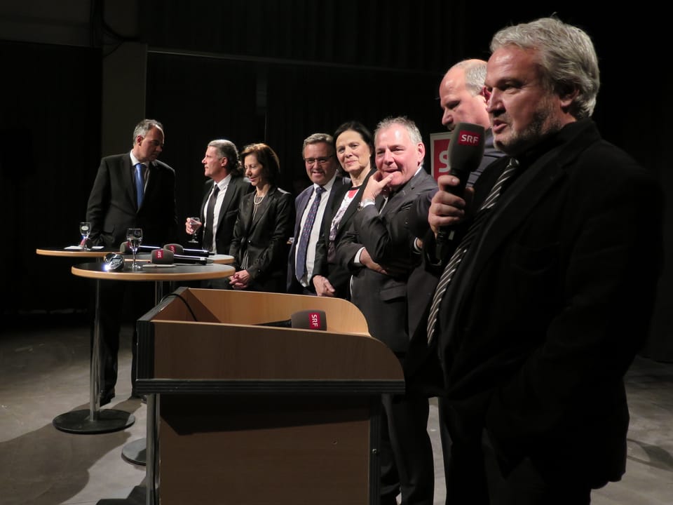 Alle Politiker stehen in einer Reihe nebeneinander, einer spricht ins Mikrofon.