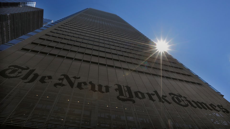 Hochhaus der New York Times in New York, Sonne scheint knapp hinter dem Gebäude hervor.