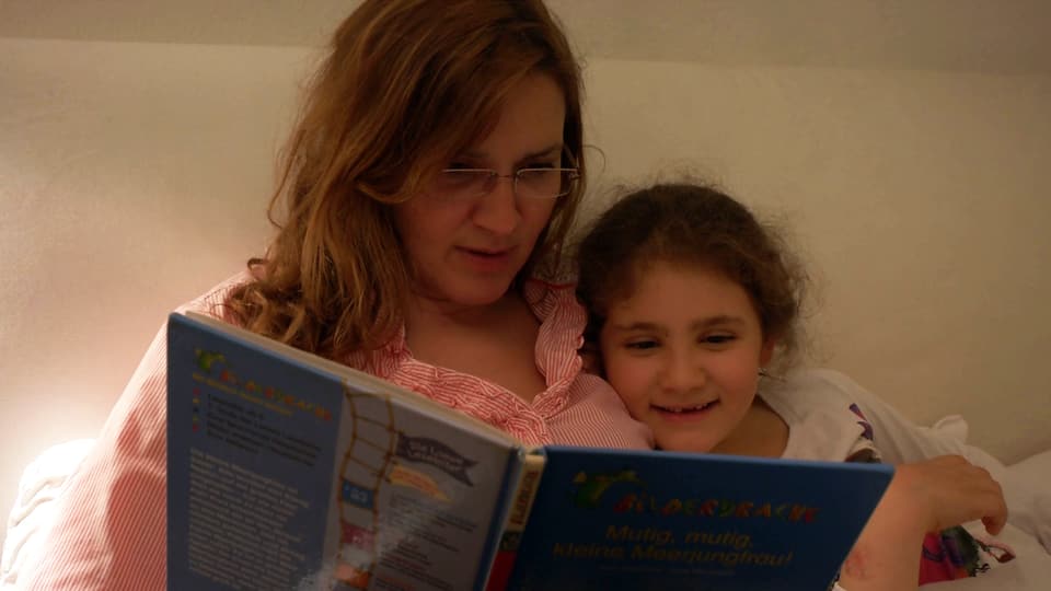 Daniela liest Alicia eine Gutenachtgeschichte vor.