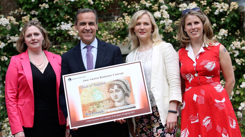 Gruppenbild mit drei Freuen und einem Mann, der eine überdimensionierte Jane-Austen-10-Pfund-Note präsentiert.