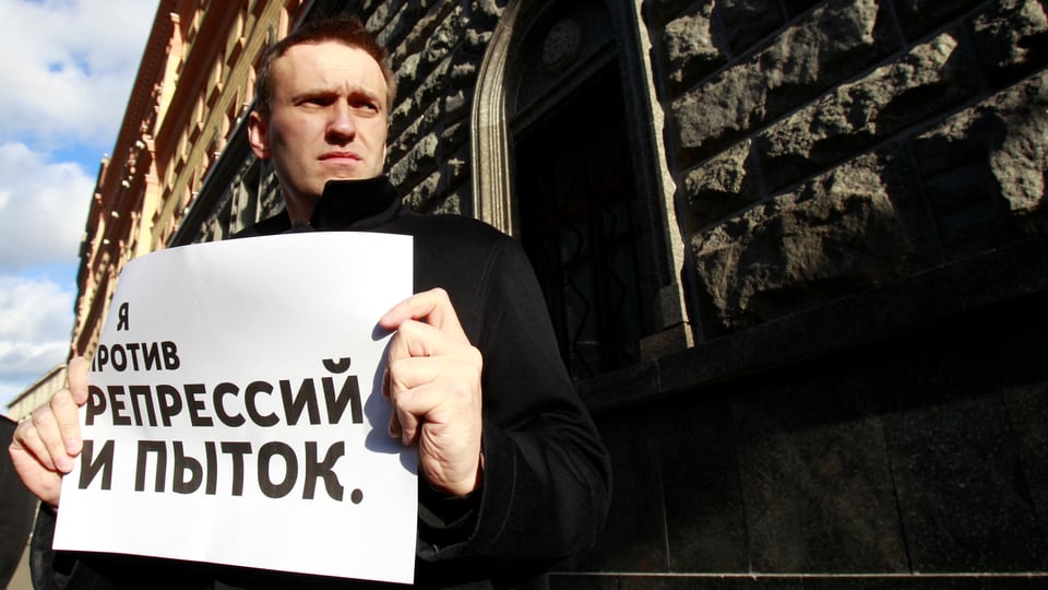 Nawalny hält ein grosse Blatt Papier in den Händen.