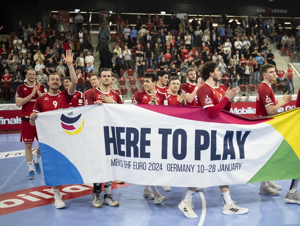 Schweizer Handballer posieren mit Banner.