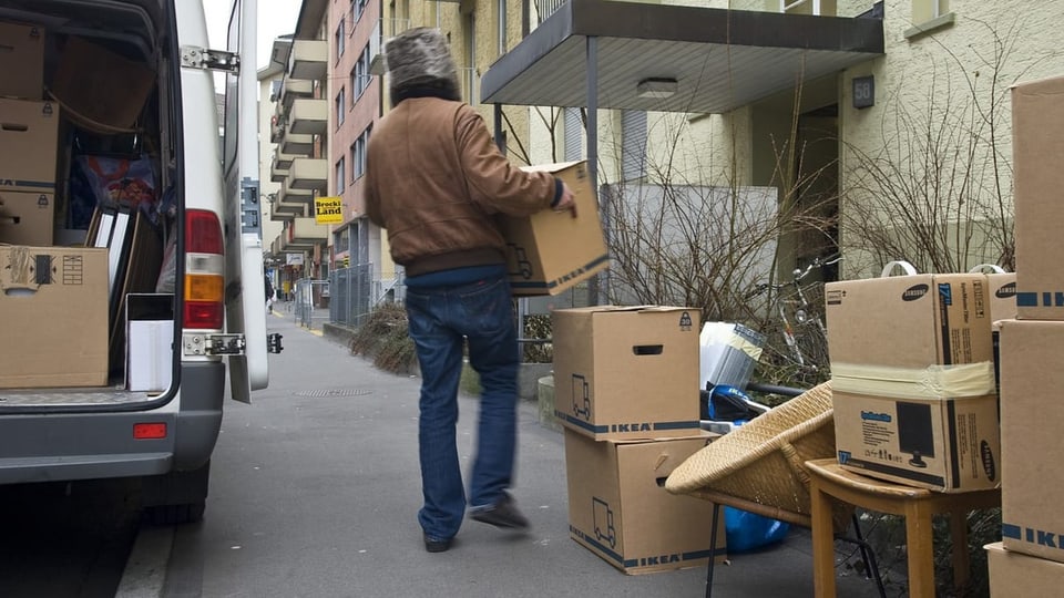 Ein Mann, der Umzugskartons aus einem Auto packt. 