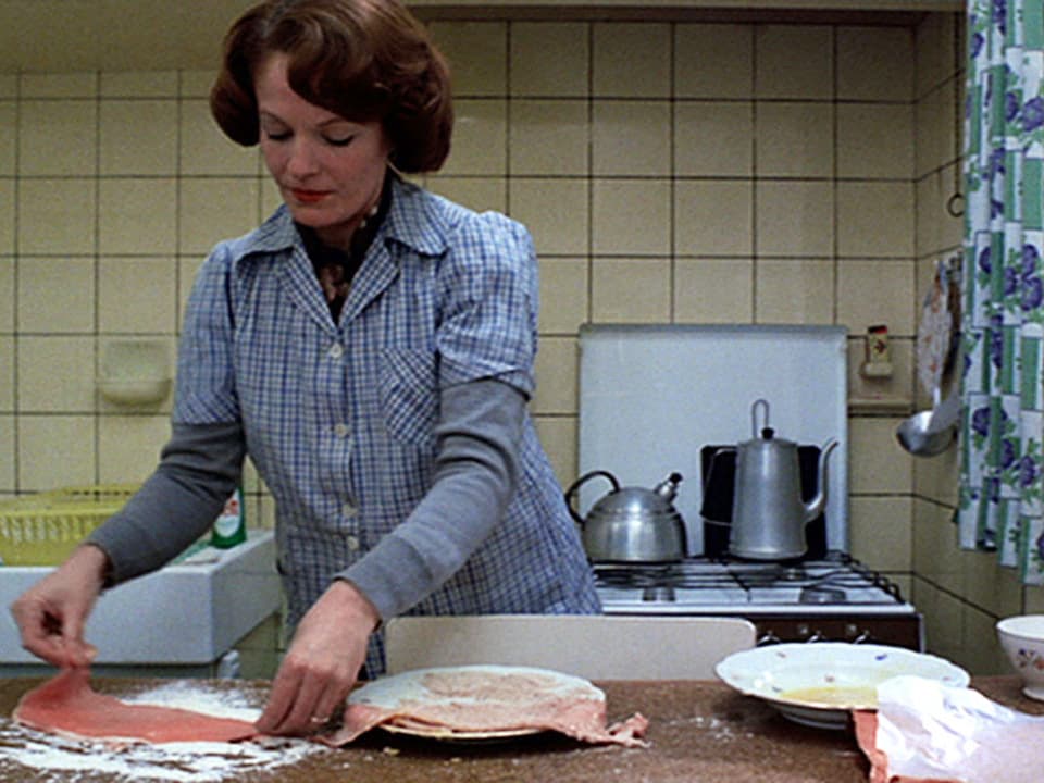 Eine Hausfrau paniert Fleisch.