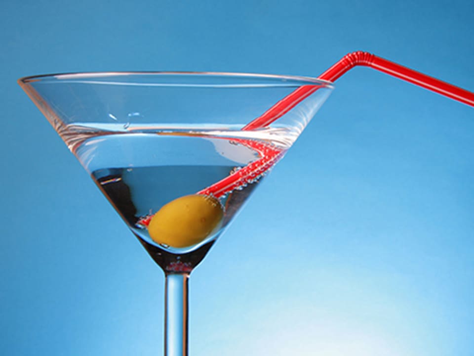 Cocktailglas mit Martini, Olive und rotem Strohhalm.