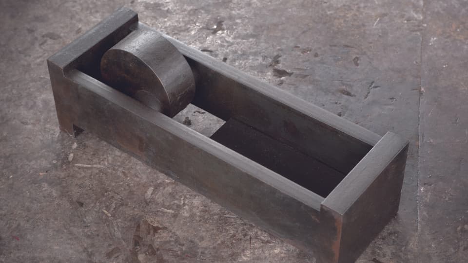 In einem rechteckigen Klotz aus Eisen steckt eine Scheibe aus Eisen
