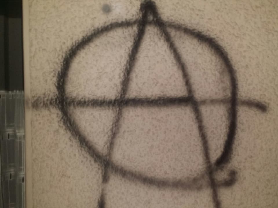 Das Anarchie-Zeichen: ein grosses A mit einem Kreis darum. 