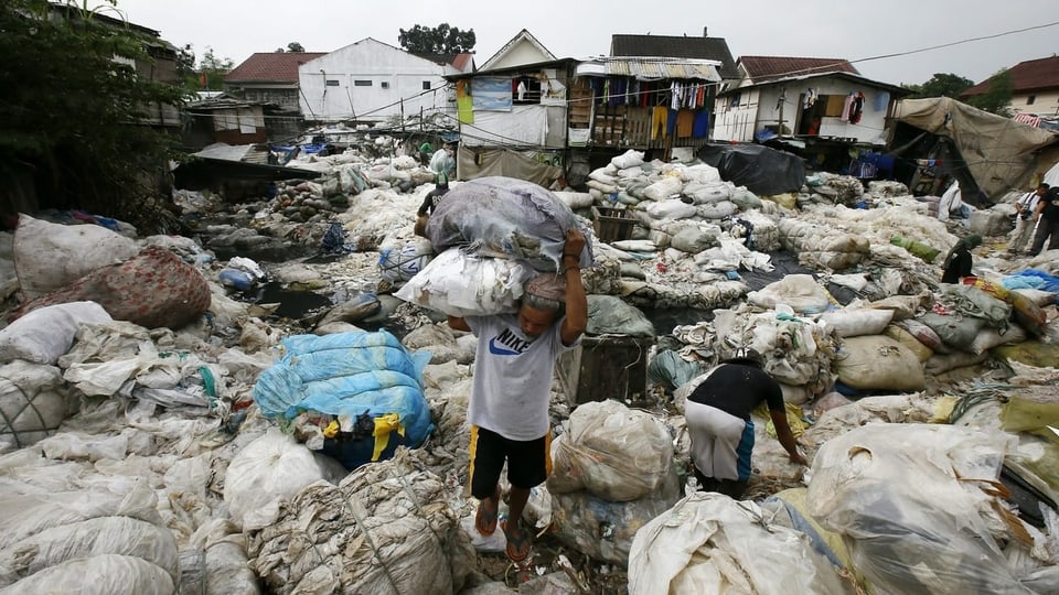 Philippinischer Mann der Plastik wegträgt. 