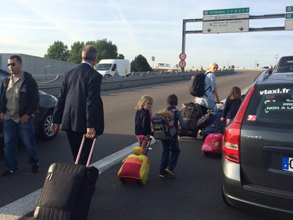 Eine Familie mit Koffern zu Fuss auf  einer Strasse unterwegs