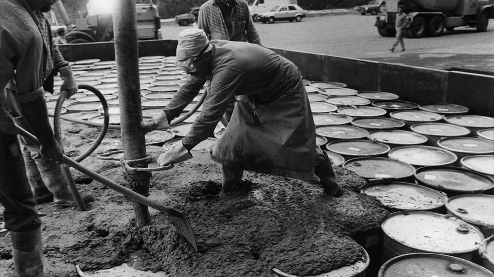 Arbeiter betonieren Fässer in der Sondermülldeponie Teuftal ein.