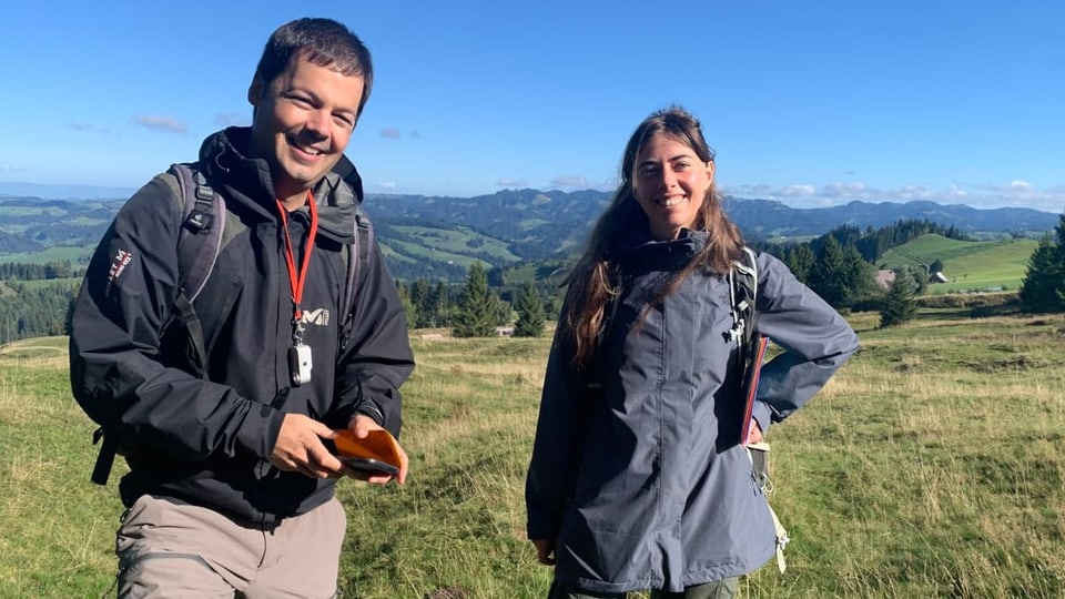 Andrin Gross und seine Forscherkollegin stehen auf einer Wiese.