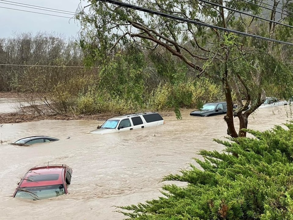 Aus dem Wasser auf einer komplett überschwemmten Strasse ragen die Dächer von weggespülten Autos.