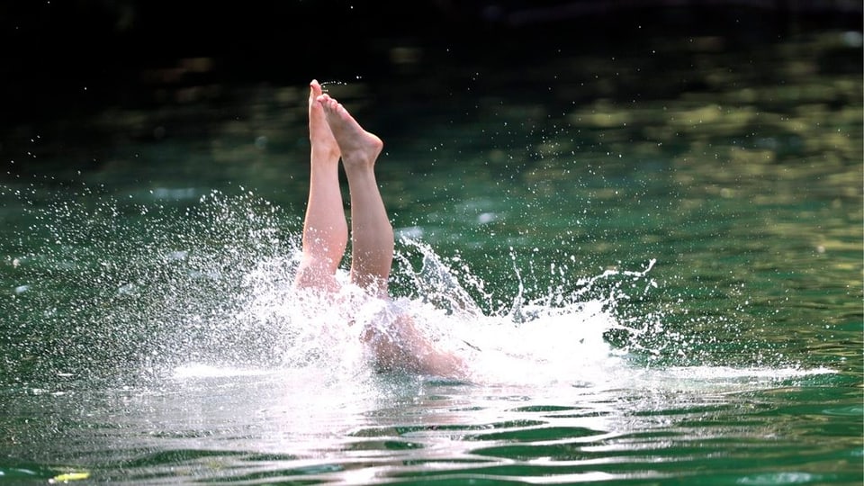 Schwimmerin kühlt sich mit einem Sprung in den See ab. 