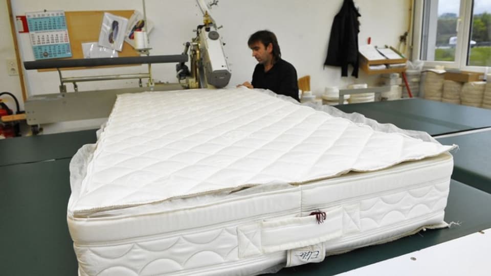 Ein Mitarbeiter der Farbrik in Aubonne näht eine Matratze zusammen.