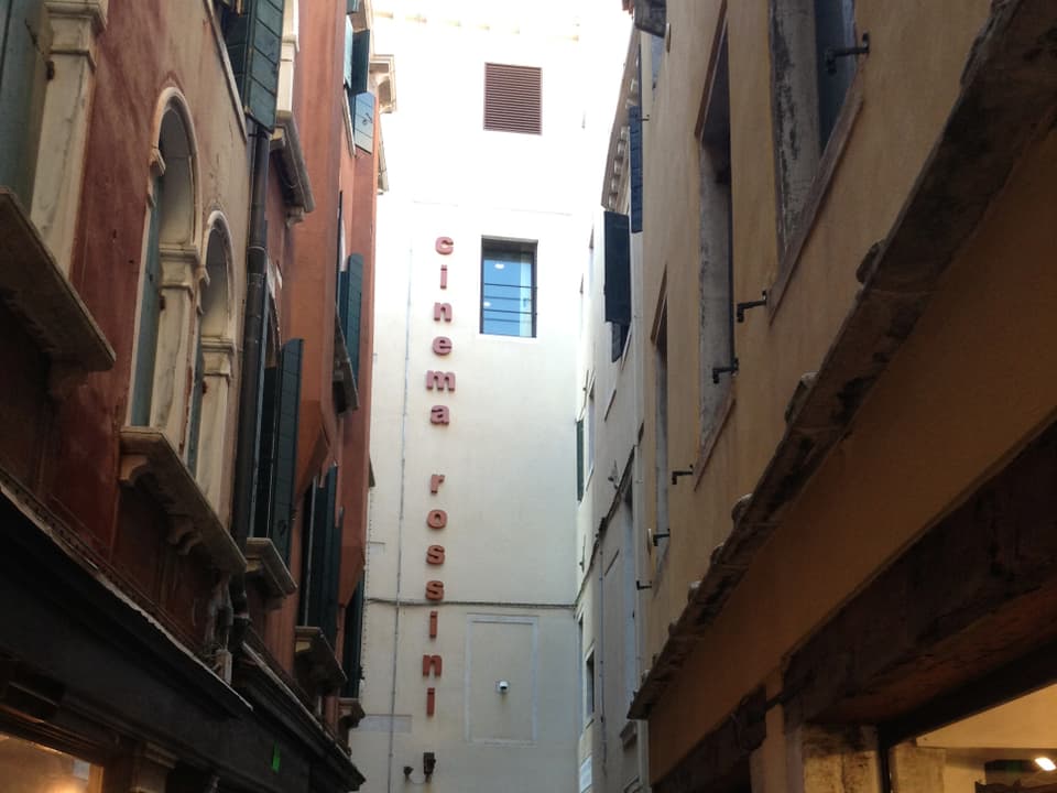 Blick zwischen Häuserfassaden auf ein Kino in Venedig