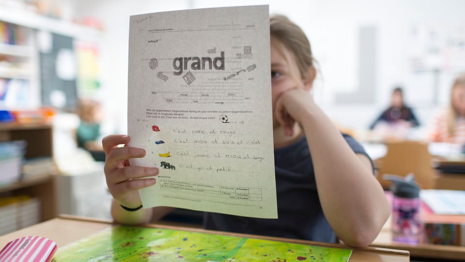 Ein Mädchen hält ein Lernblatt mit französischen Wörtern in der Hand. 