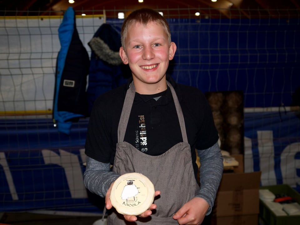Blonder Junge präsentiert stolz Käse mit selbst kreiertem Ettikett.