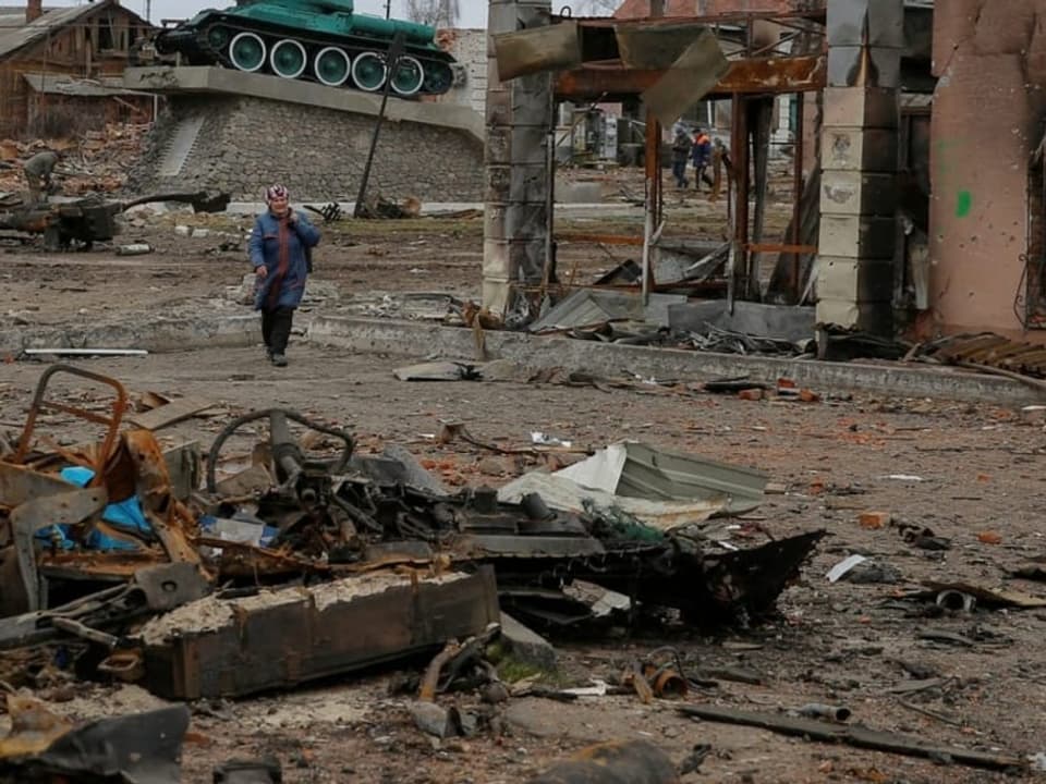 Eine Einwohnerin läuft zwischen Gebäuden, die durch russischen Beschuss beschädigt wurden