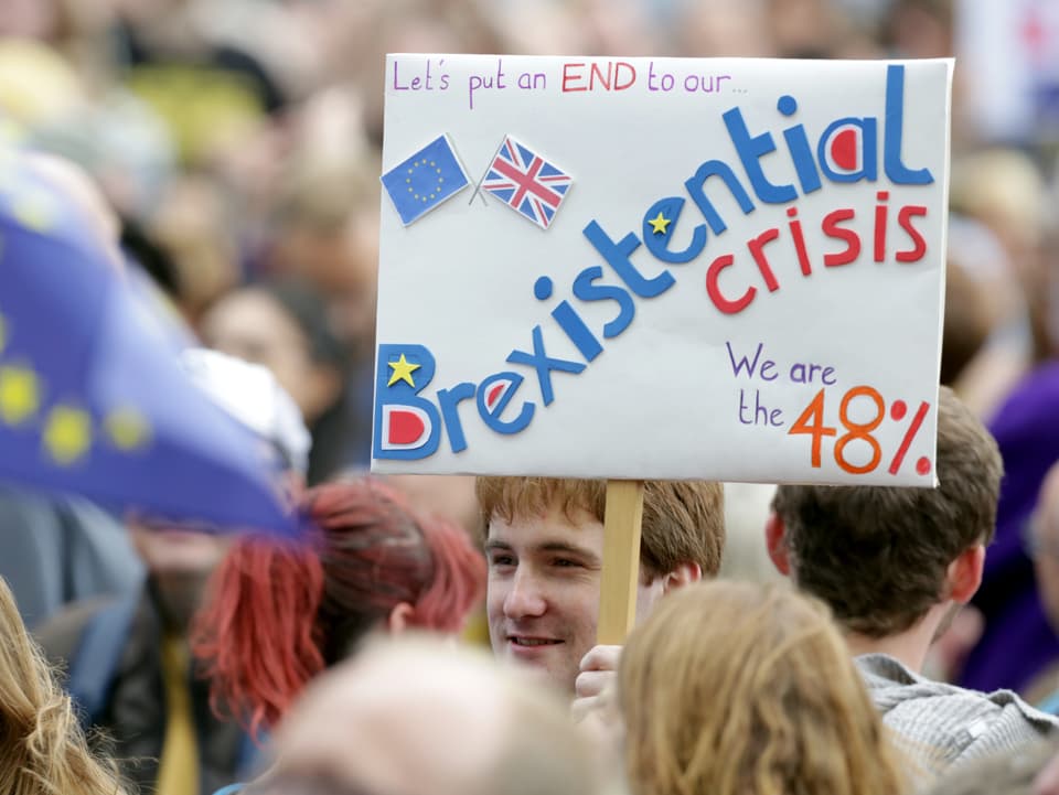 En Mann hält ein Transparent mit der Aufschrift «Let's put an end to our Brexistential crisis».