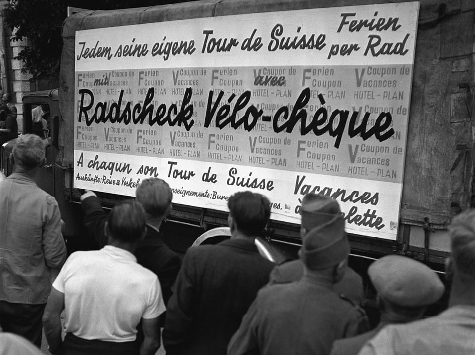 Zuschauer der Velorundfahrt 1942 betrachten ein Hotelplan-Werbeplakat.