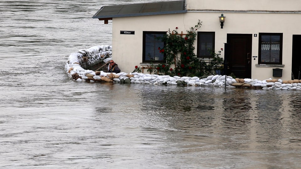 Ein Mann hinter einer Hochwasser-Schutzmauer vor seinem Haus